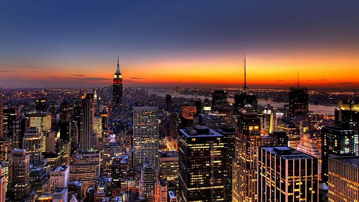 Vista aérea de uma grande cidade ao entardecer, com prédios iluminados